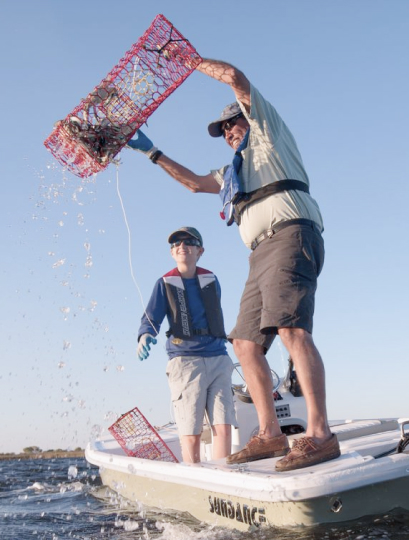 ボートの上でたち、漁の仕掛けを回収する2人の写真