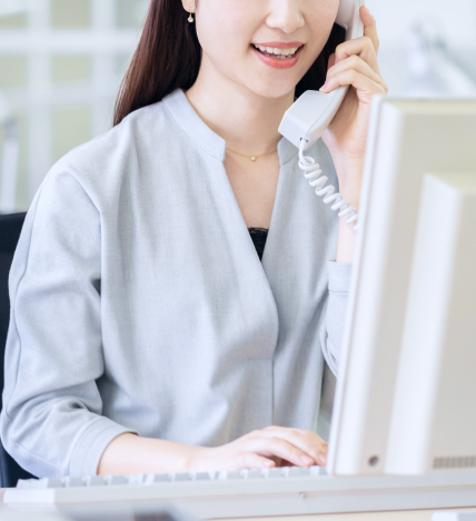 パソコンを見ながら電話をする女性の写真