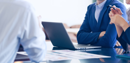 パソコンや資料を広げ、会議をする3名の写真