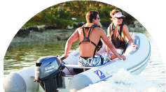 船外機のついたボートに乗る男女2人の写真